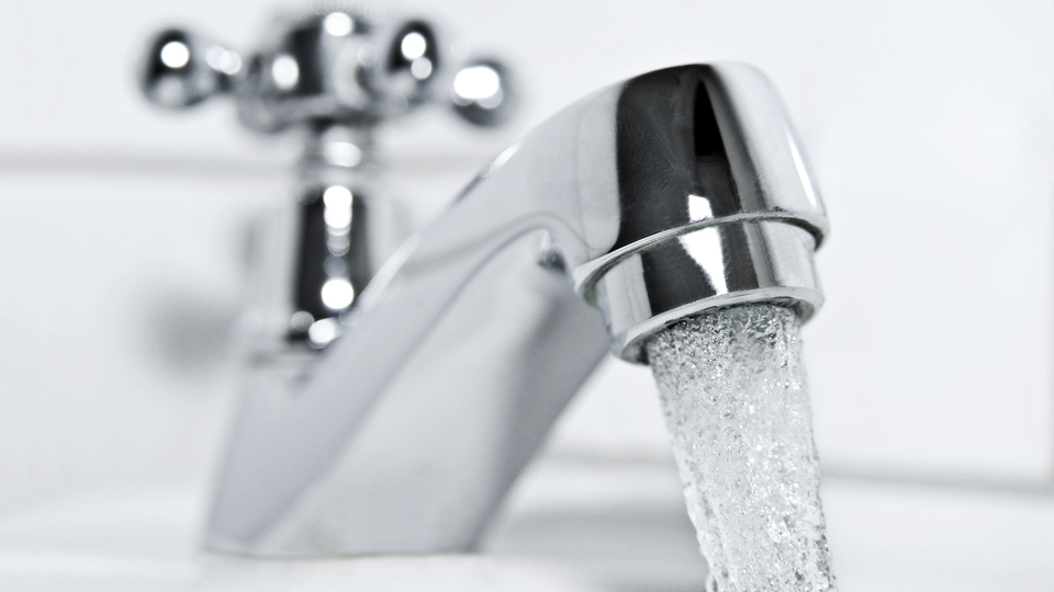 drinking water flows from a chrome water tap.