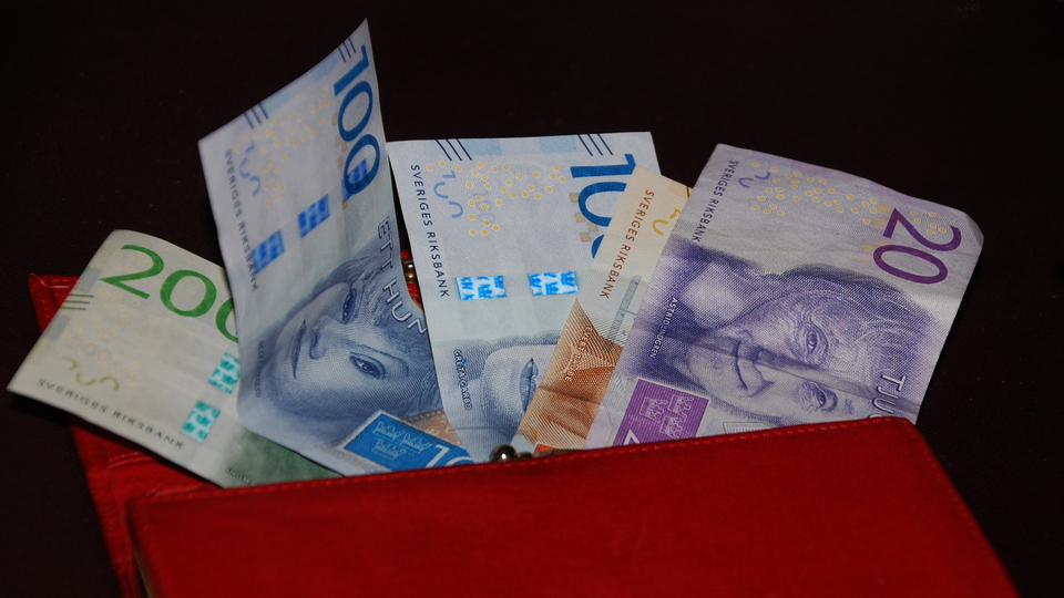 En röd plånbok fylld med pengar