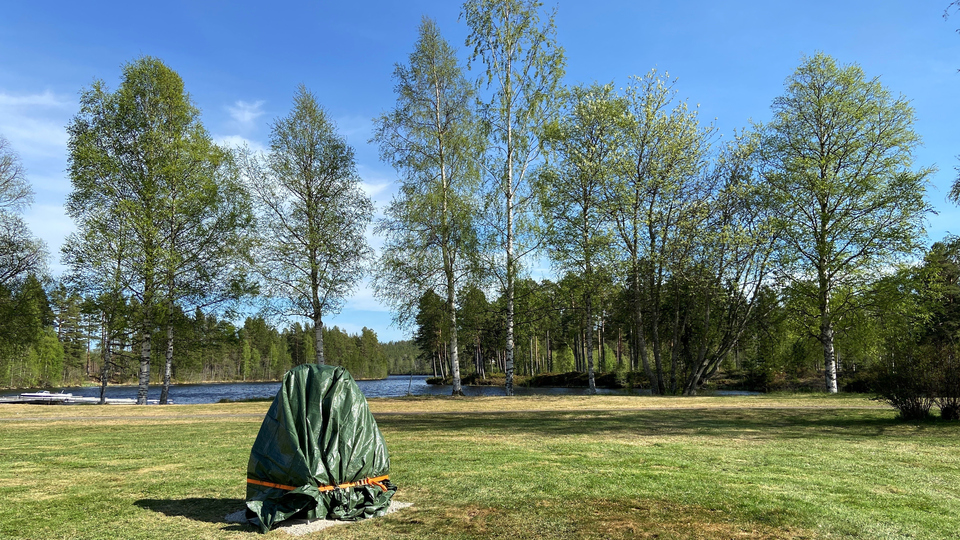 En övertäckt staty på en gräsmatta vid Ljusnans strand.