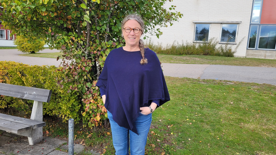 En kvinna står bredvid en träbänk.