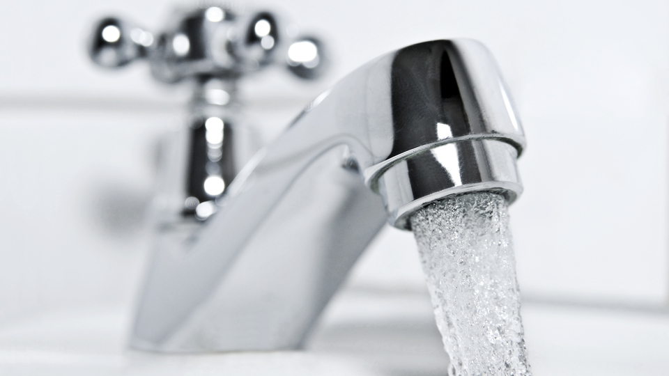 drinking water flows from a chrome water tap.
