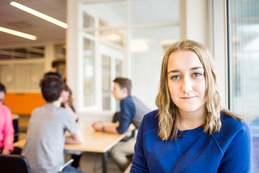 Allvarlig flicka som sitter i fikarum på skola