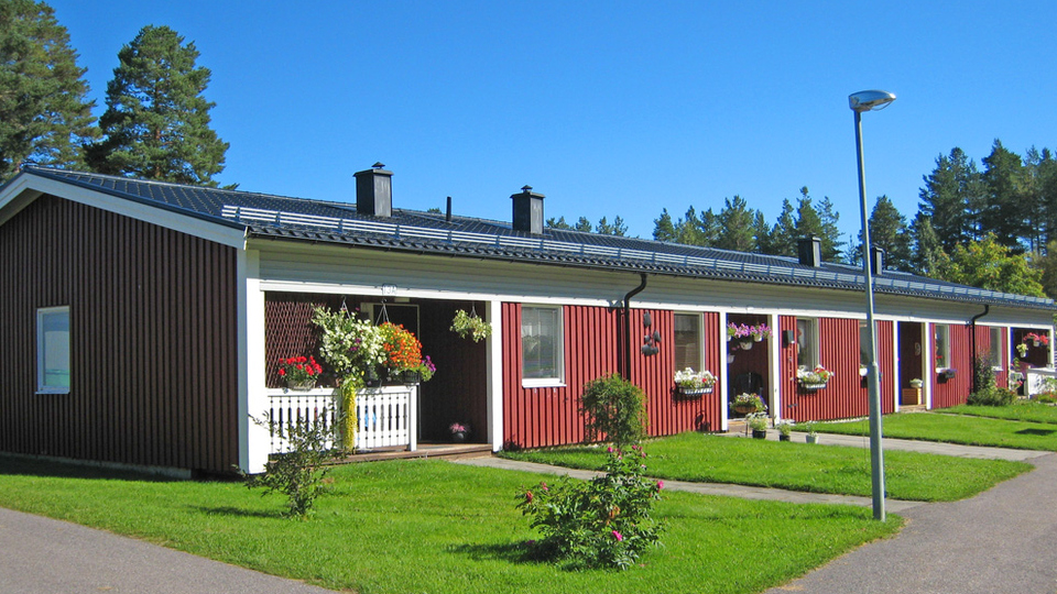 Röda radhus med gröna gräsmattor framför.