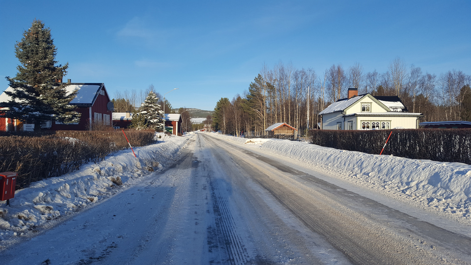 Vit vinterväg med snöplogkanter genom byn Vemhån