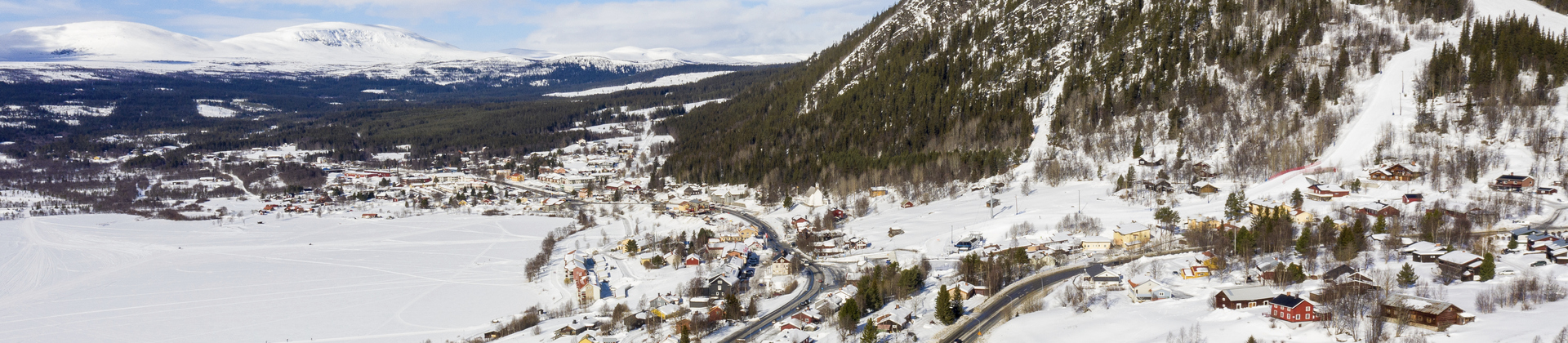 Drönarbild över Funäsdalen med Funäsdalsberget i fonden. Villor och vägar mellan snötäckt sjö och skogsklätt berg med snötäckta backar.