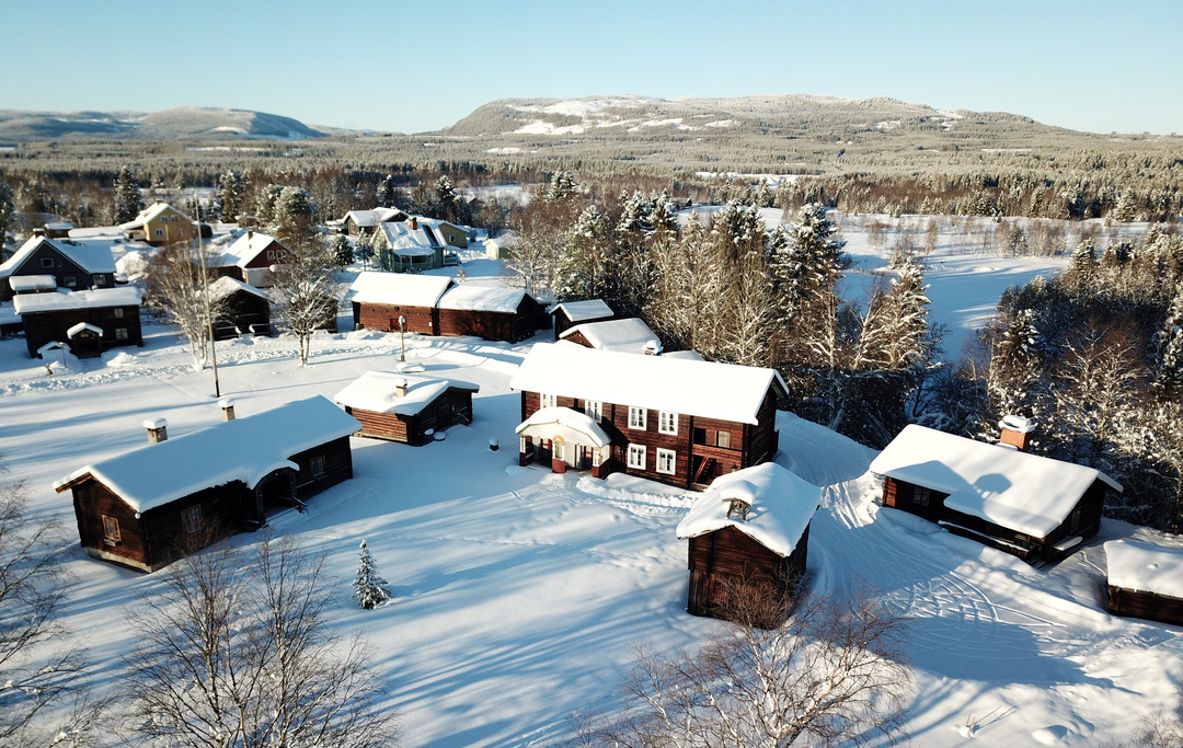 Drönarbild över snötäckta timmerhus på en gård i Hede.