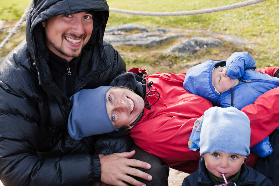 En mamma, pappa och två små barn som sitter tillsammans ute på ett fjäll