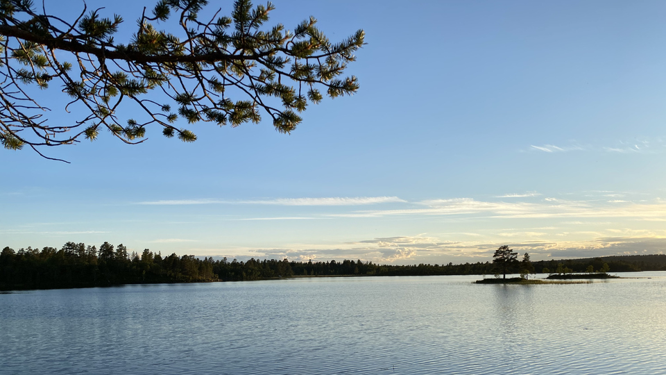 Spegelblank sjö med öar i kvällsljus.