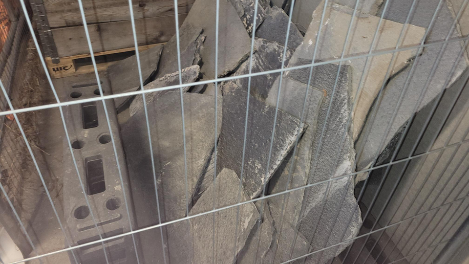 Ett gäng stenar, skiffer, i en metallbur.