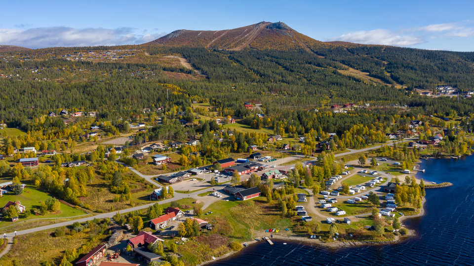 En flygbild över by vid vatten, fjäll i bakgrunden