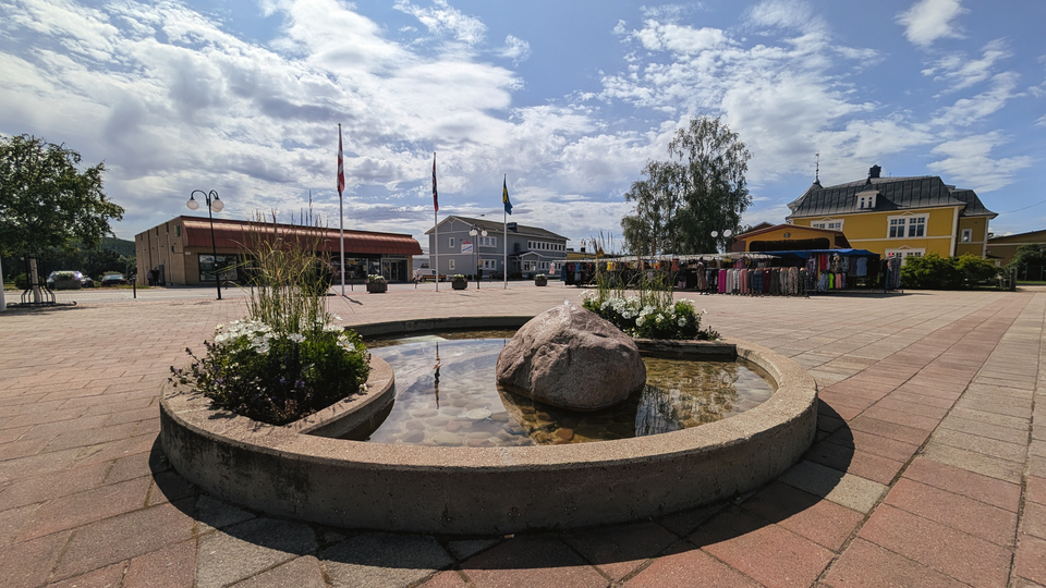 En fontän av sten på ett torg omgivet av byggnader.