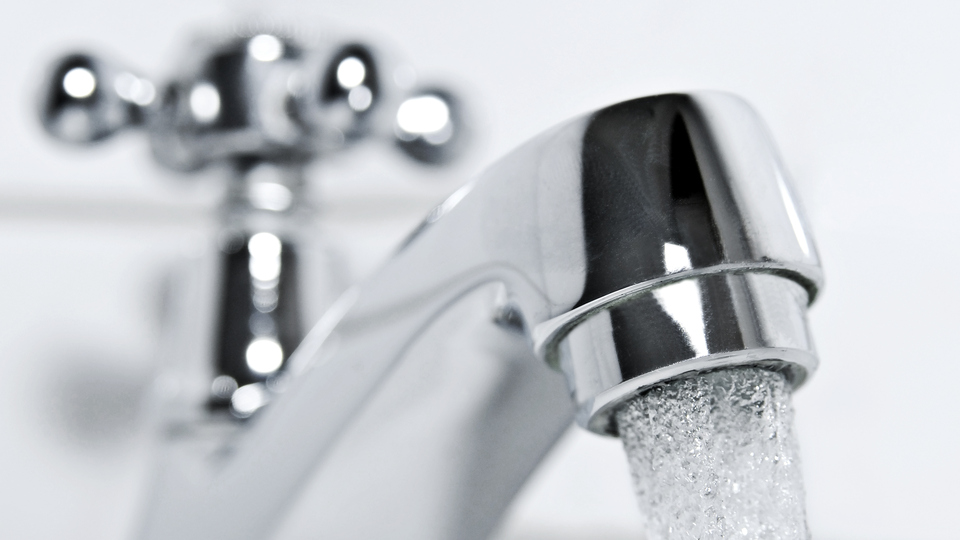 drinking water flows from a chrome water tap.