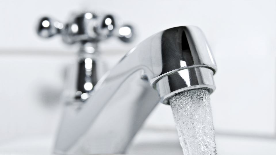 drinking water flows from a chrome water tap.
