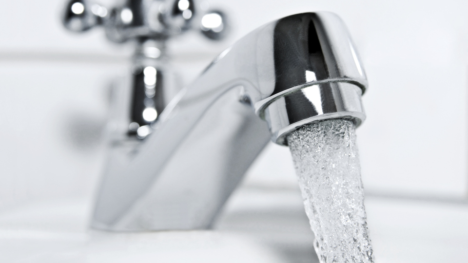 drinking water flows from a chrome water tap.