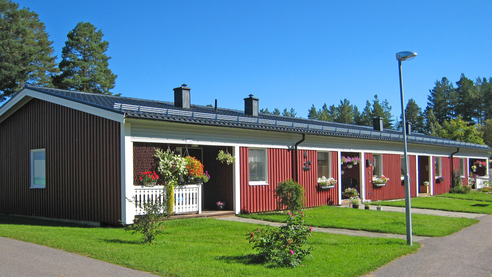 Röd radhuslänga med gröna gräsmattor framför.