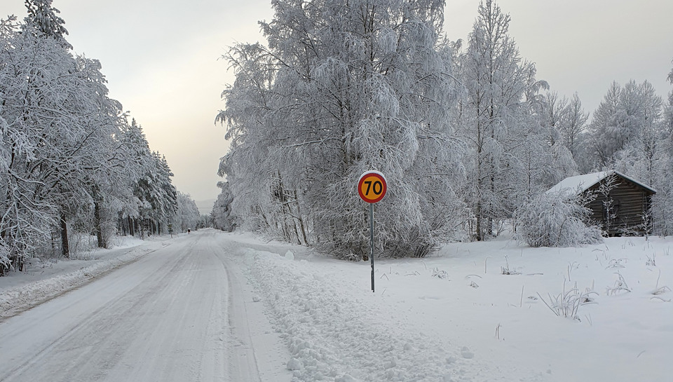 Väg med 70-skylt i vintrigt landskap