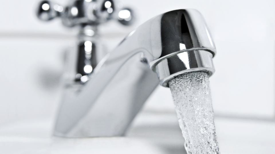 drinking water flows from a chrome water tap.