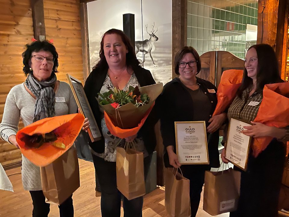 Fyra damer med blommor och diplom i famnarna.