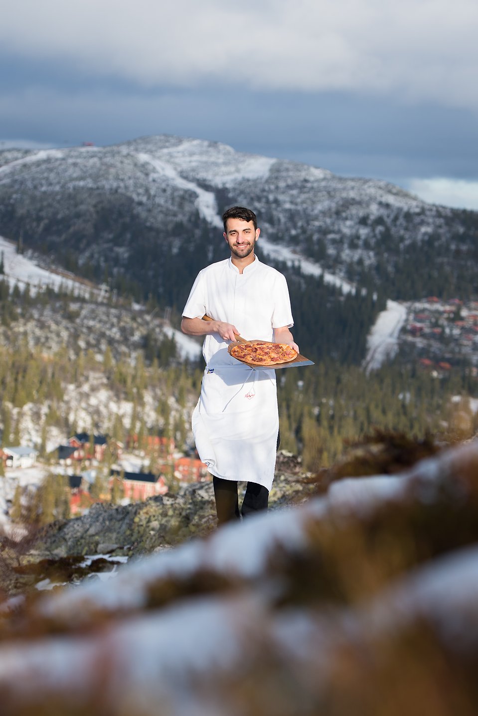 Man stoltserar med en pizza med fjället i bakgrunden