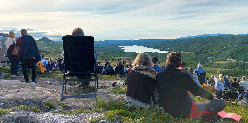 Utomhuskonsert på högfjället i Hamra där publiken sitter i gröngräset med fantastisk utsikt över fjälltopparna. 